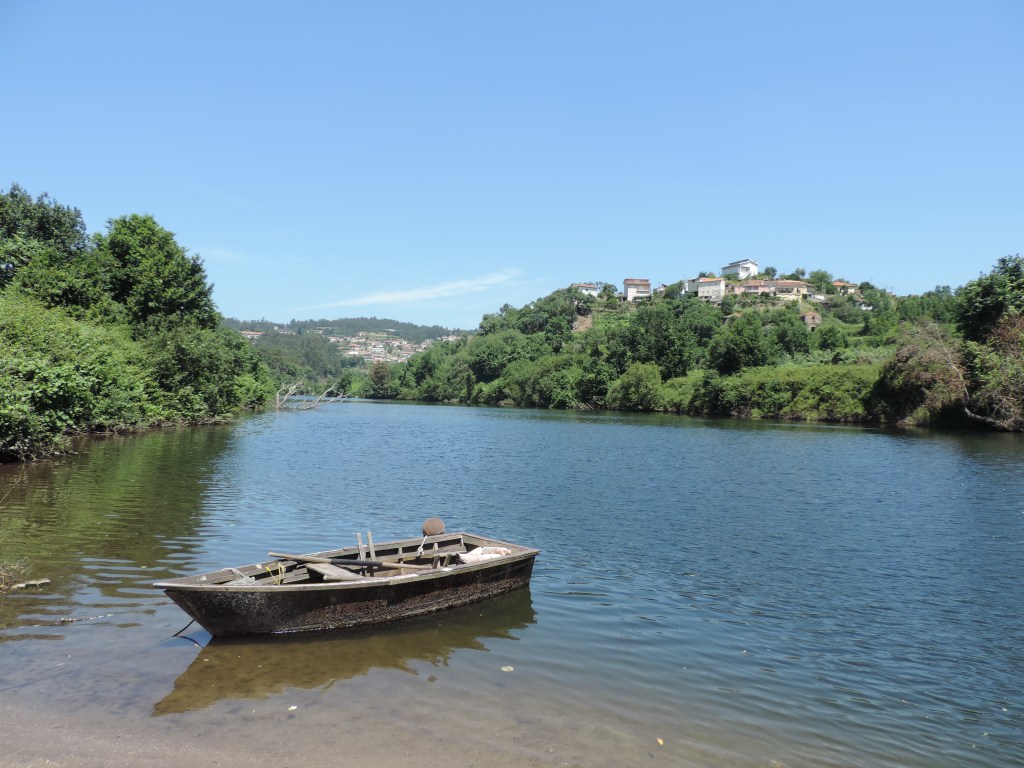 Lodo-rivier met verlaten bootje en groene oevers.
