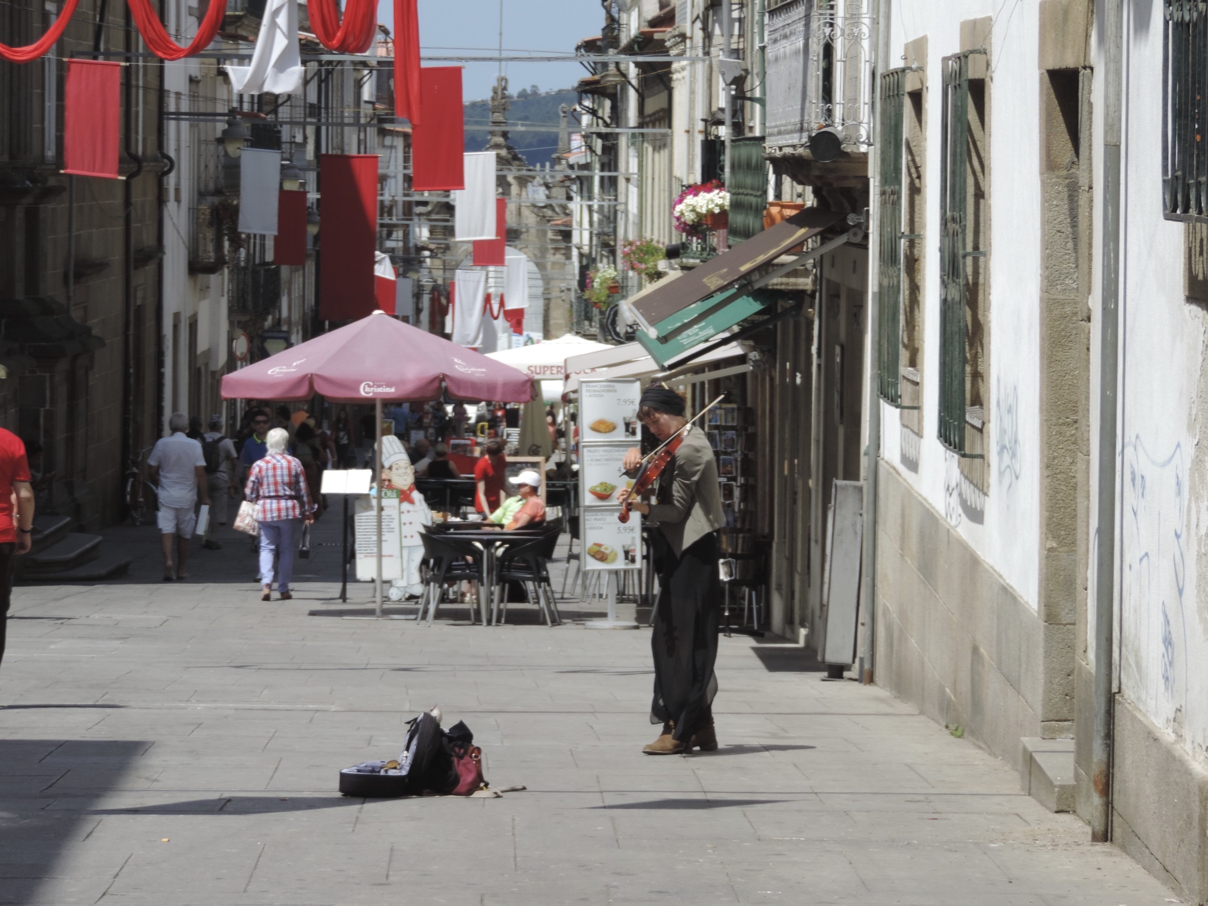 Afhellende straat met straatmuzikante die viool speelt. 