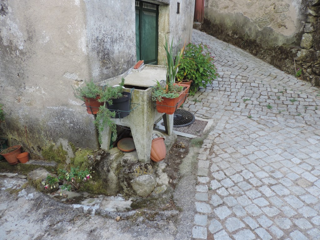 Villa Pouca da Beira: straathoek met oude wasbak en bloemen.