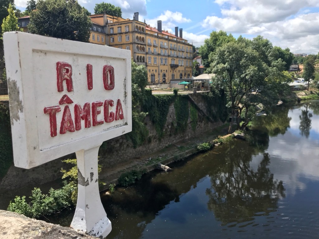 Wit bord me in rode letters “Tâmega” op brug over rivier.