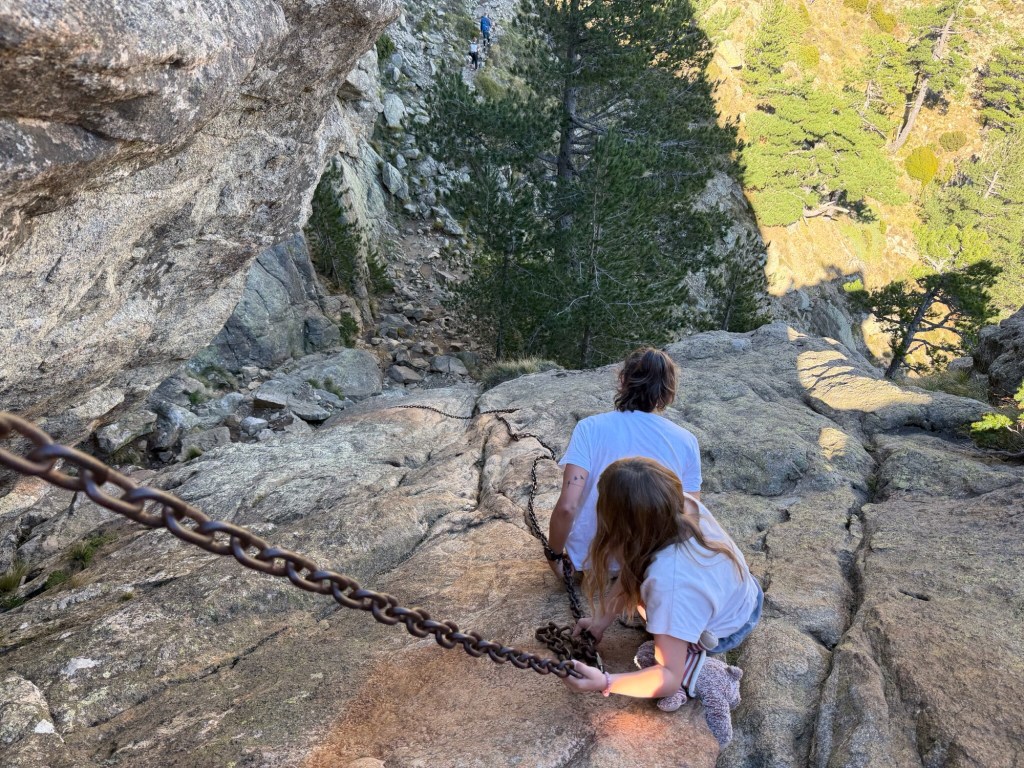 Toeriste met kind dalen af langs kettingen aan de rotsen. 