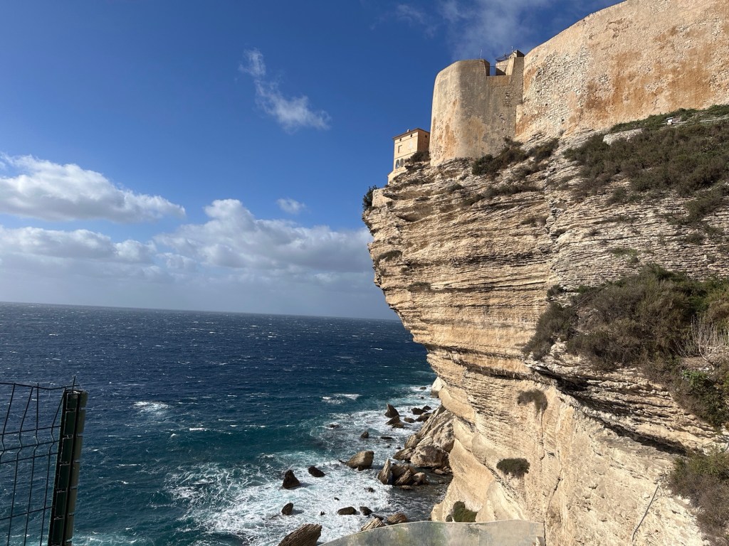 Huizen op rotsen die over de zee hangen. 