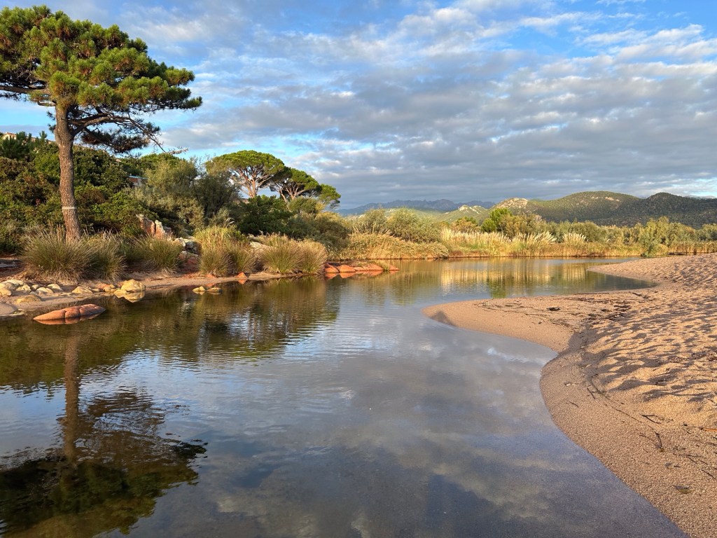 Meertje en rivier achter zandstrand.