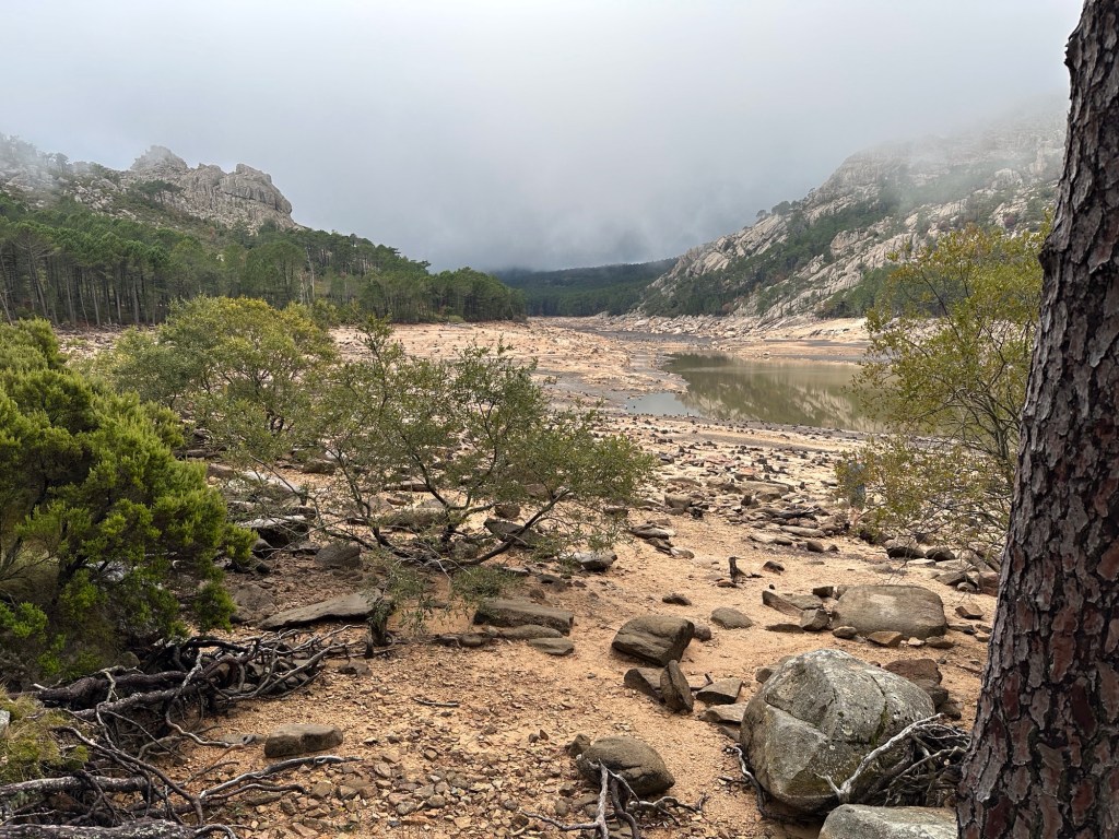 Panorama met bergen, lage wolken, leeg stuwmeer. 