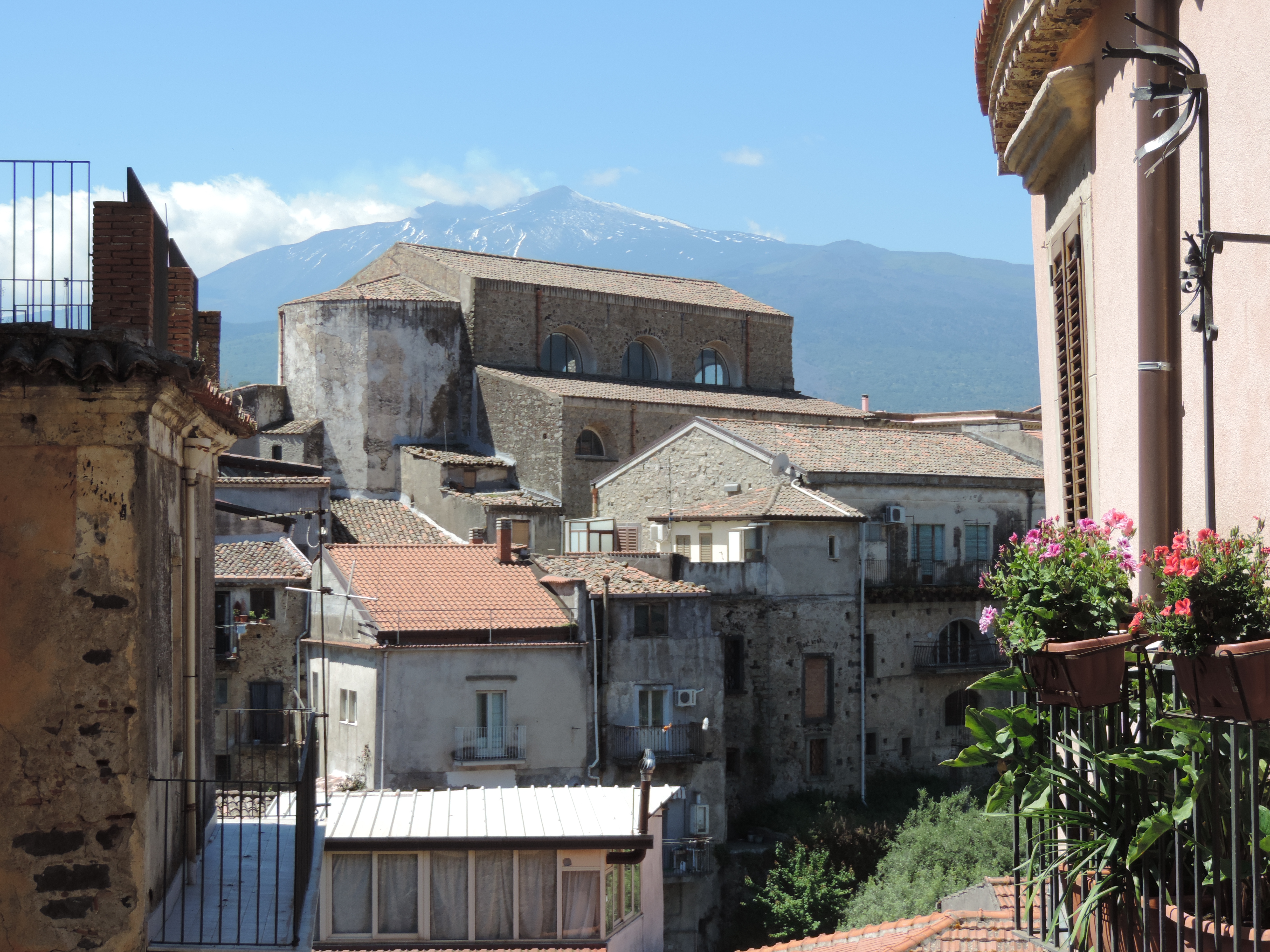 Zicht op daken en huizen van Castiglione di Sicilia met Etna op achtergrond.