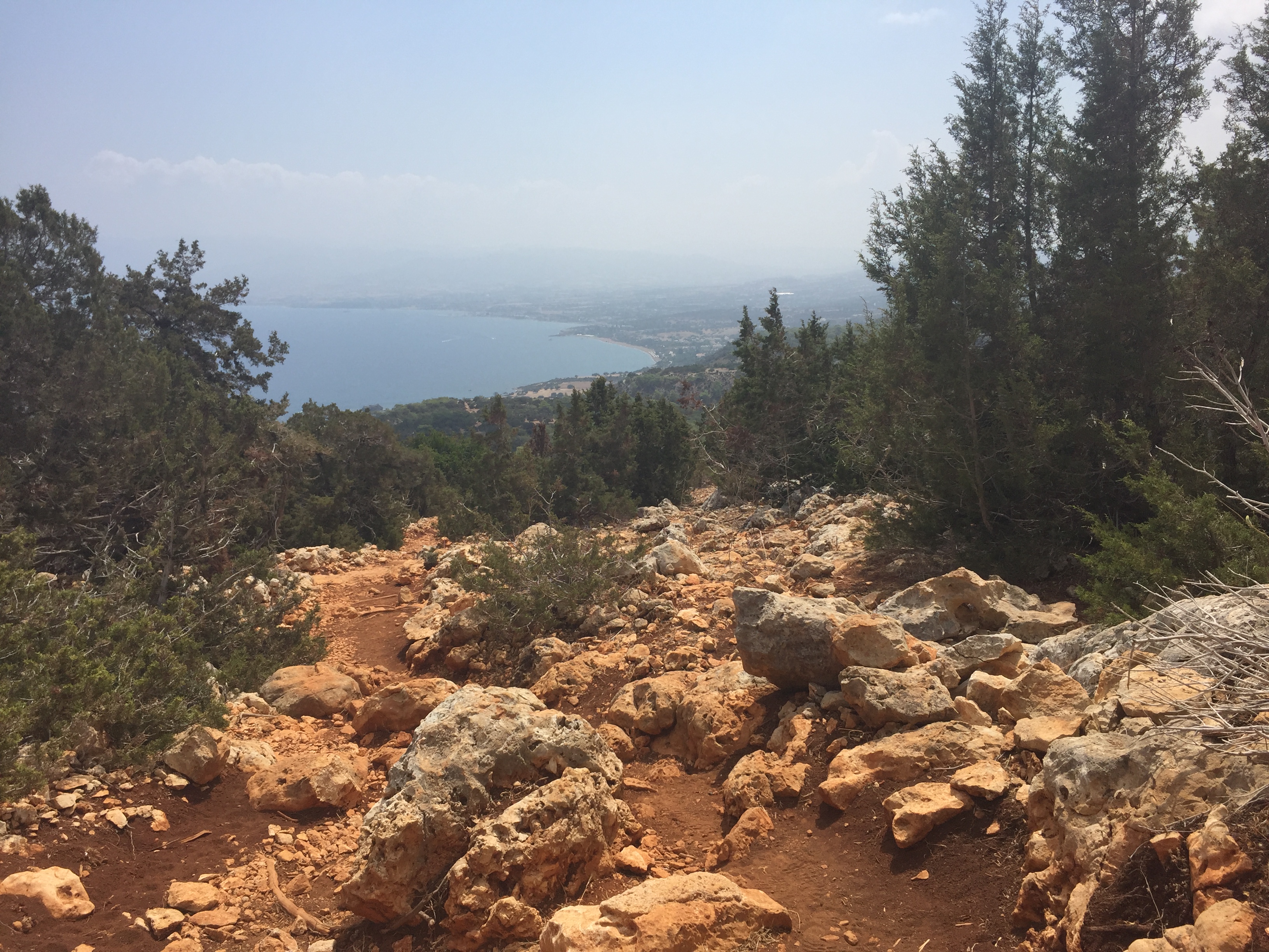 Rotsachtig afdalen pad met zee op achtergrond.