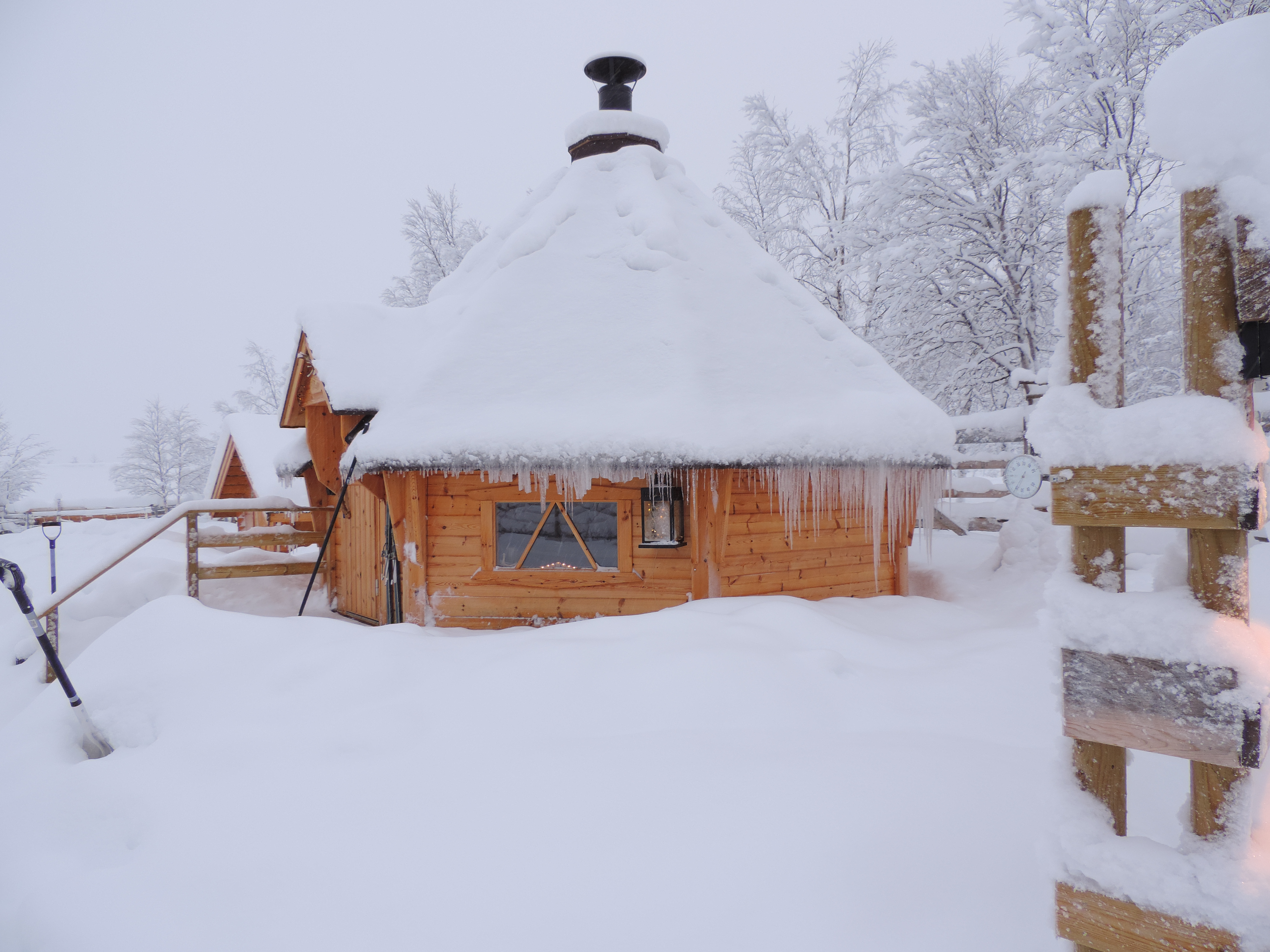 Houten huisje onder sneeuw en ijs.