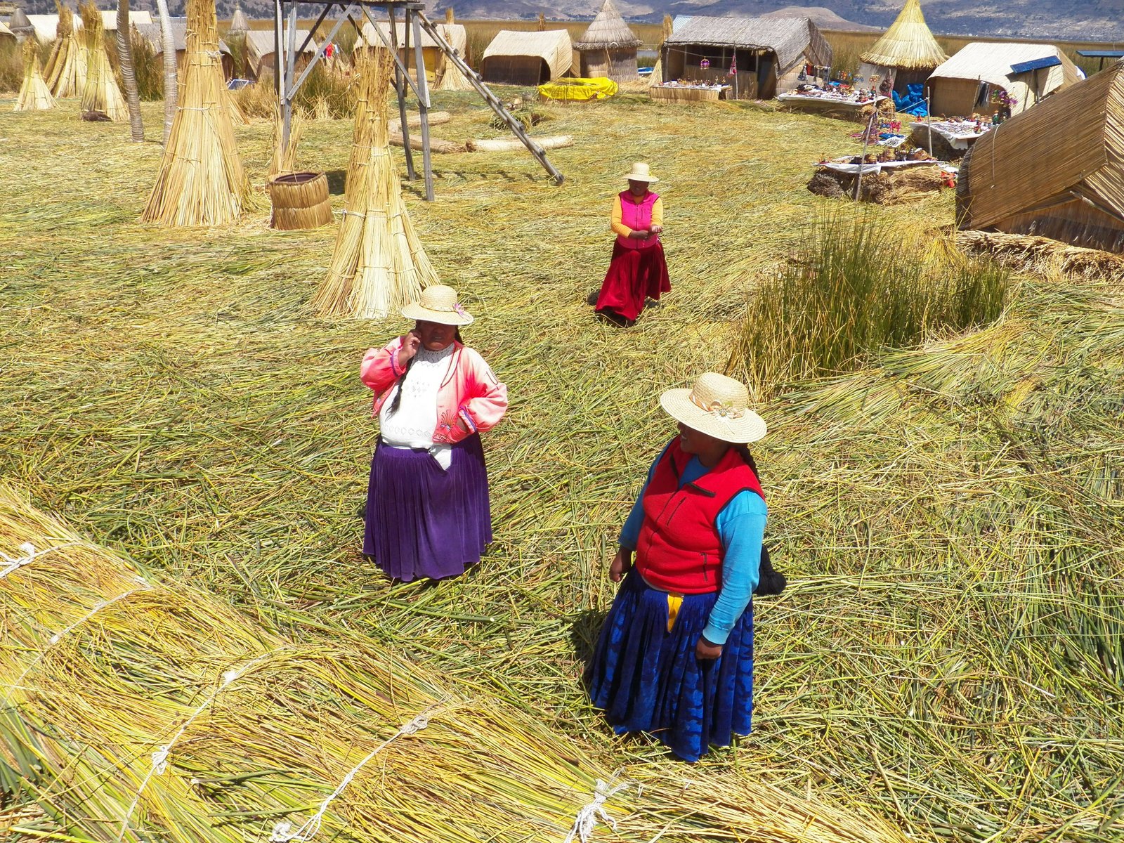 Drie vrouwen in lokale, kleurrijke klederdracht op rieten eiland.