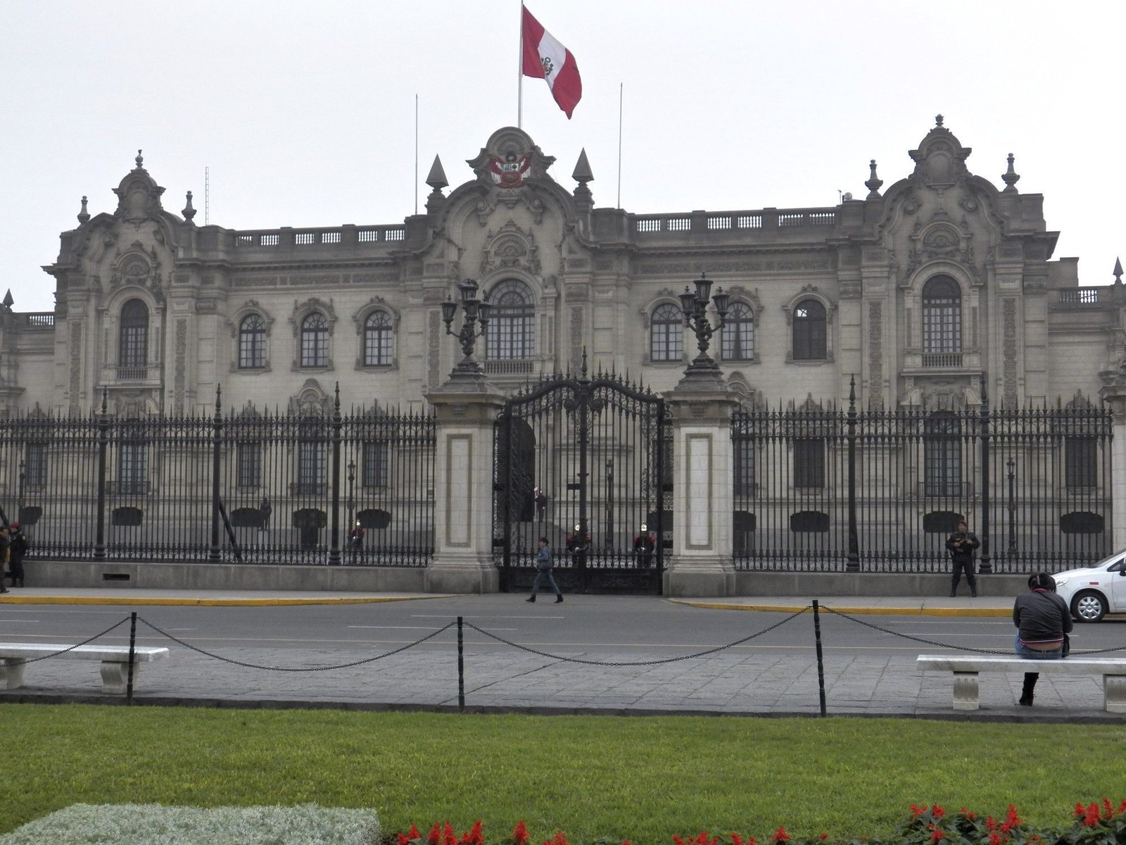 Palacio de Gobierno: statig grijs gebouw met Peruviaanse vlag en ijzeren traliewerk er voor.