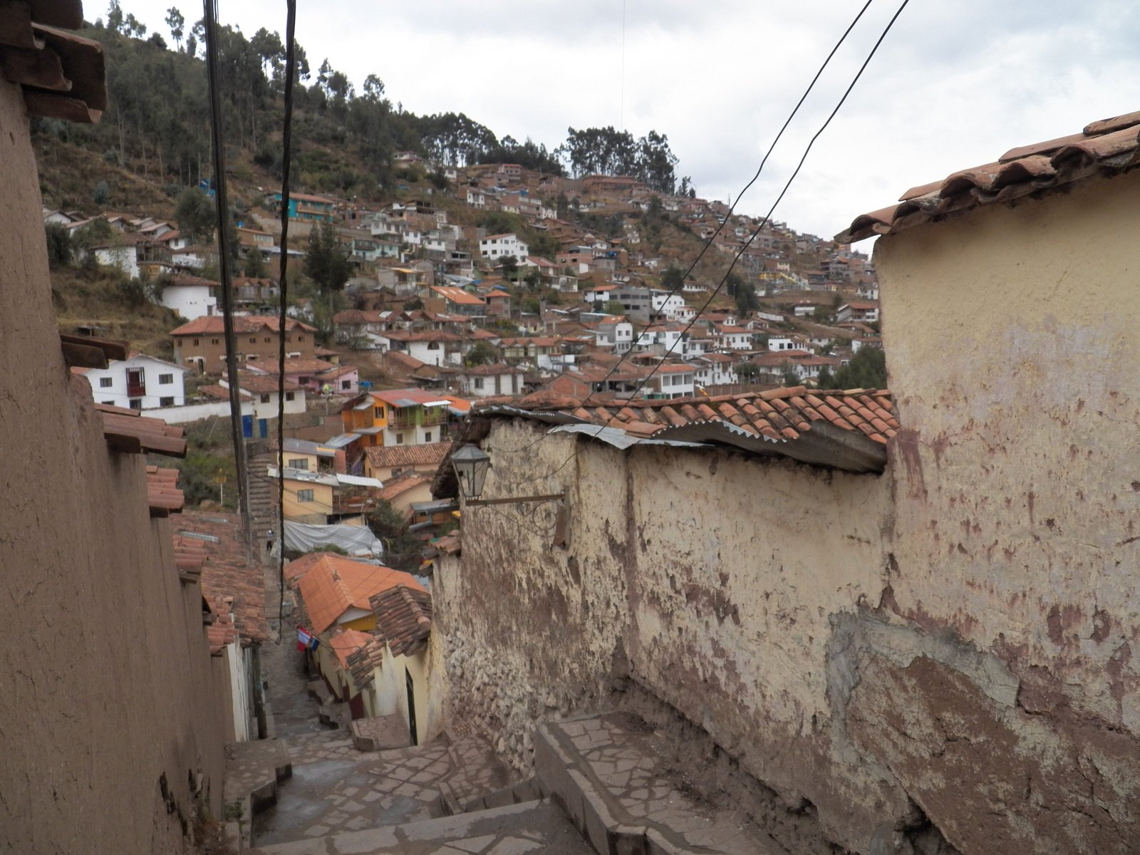 Smaal straatje met trappen en zicht op een deel van Cusco op de heuvelflank.