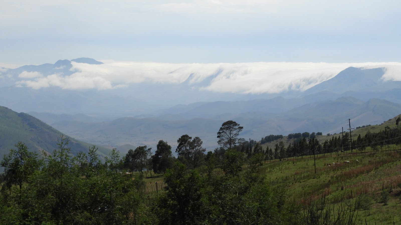 Landschap met bergen en witte wolken op de achtergrond.