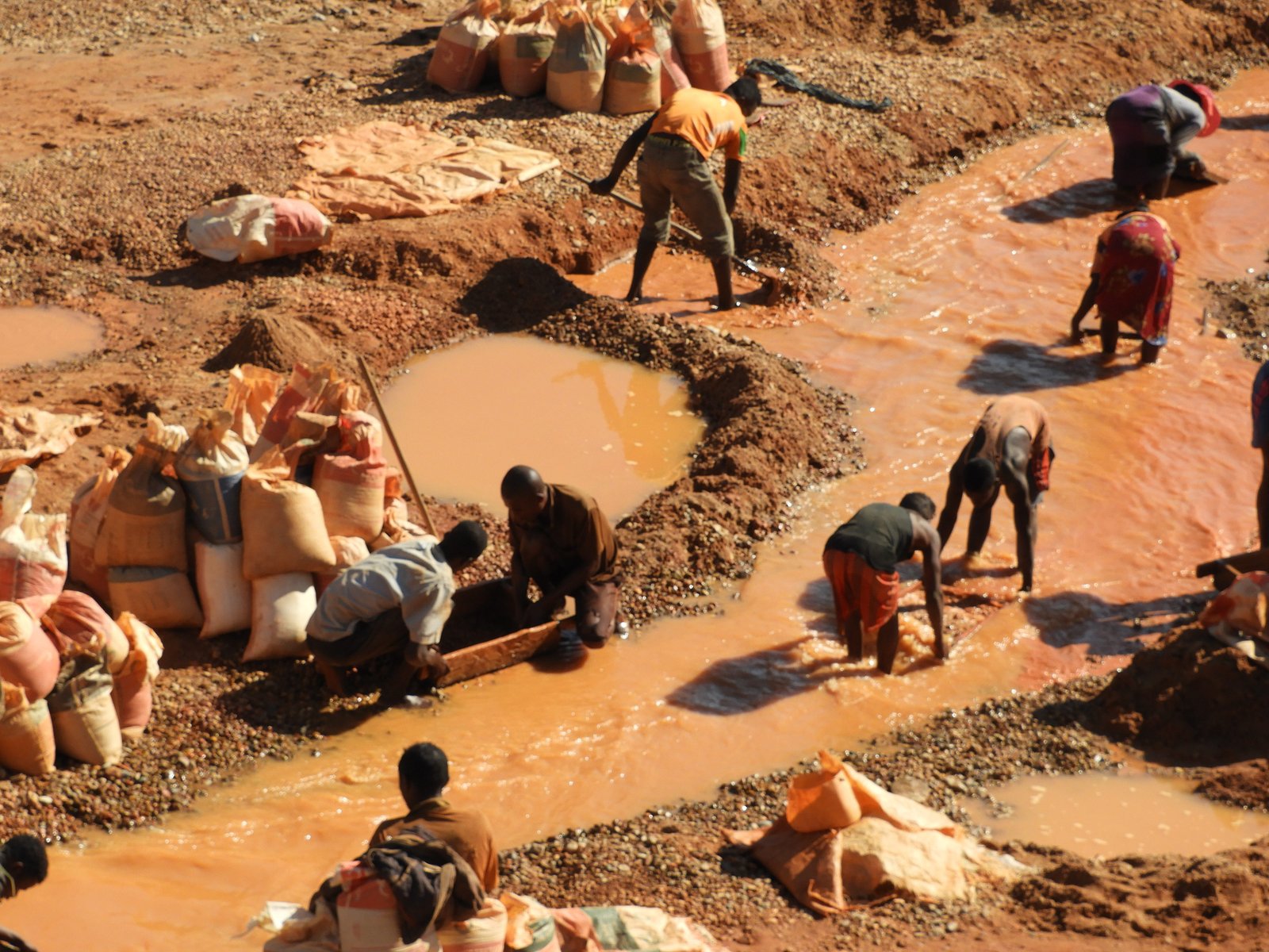 Mannen, vrouwen pannen een bruinrode rivier uit.