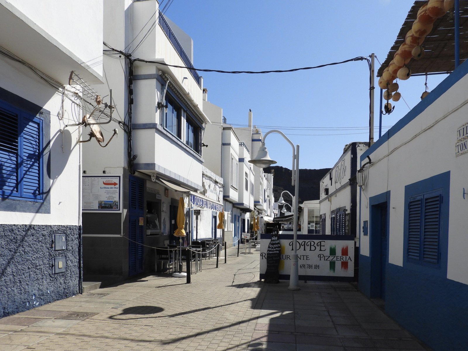 Toeristisch straatje met witte huizen / terrasjes.