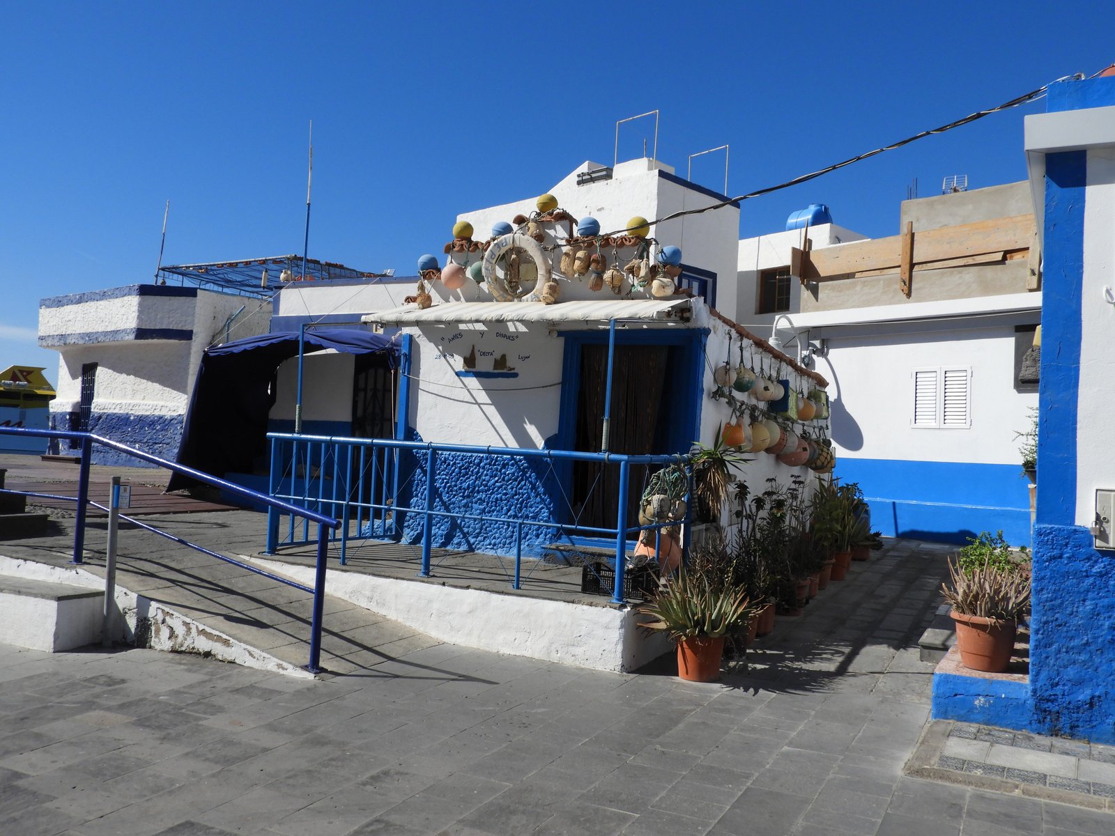 Wit huis met blauwe onderkant en boeien aan het dak.