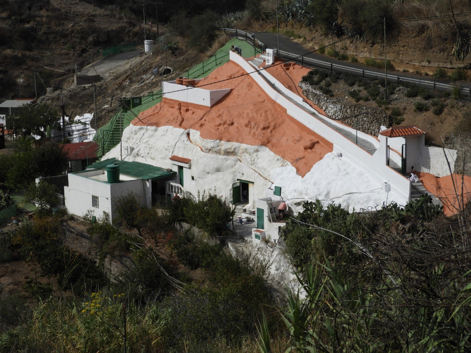 Witte rots/grot met huis met rood dak er tegenaan.