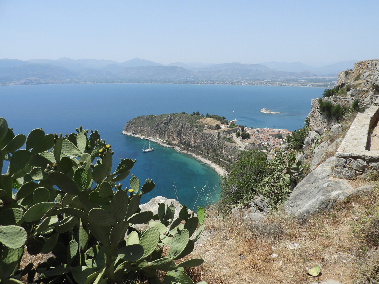 Tips van rotsen in de zee met Nafplio aan de zijkant.