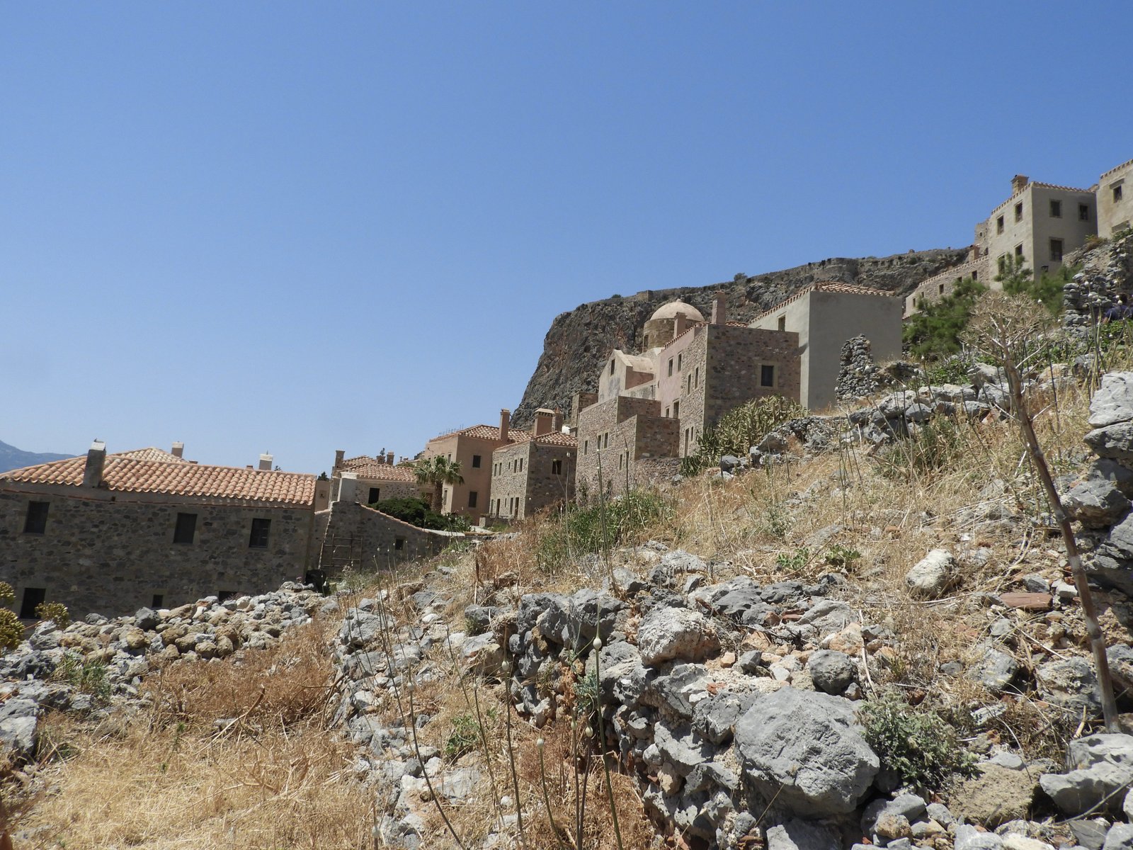 Rotshelling rechts, deels met de laatste huizen van Monemvasia deels begroeid.