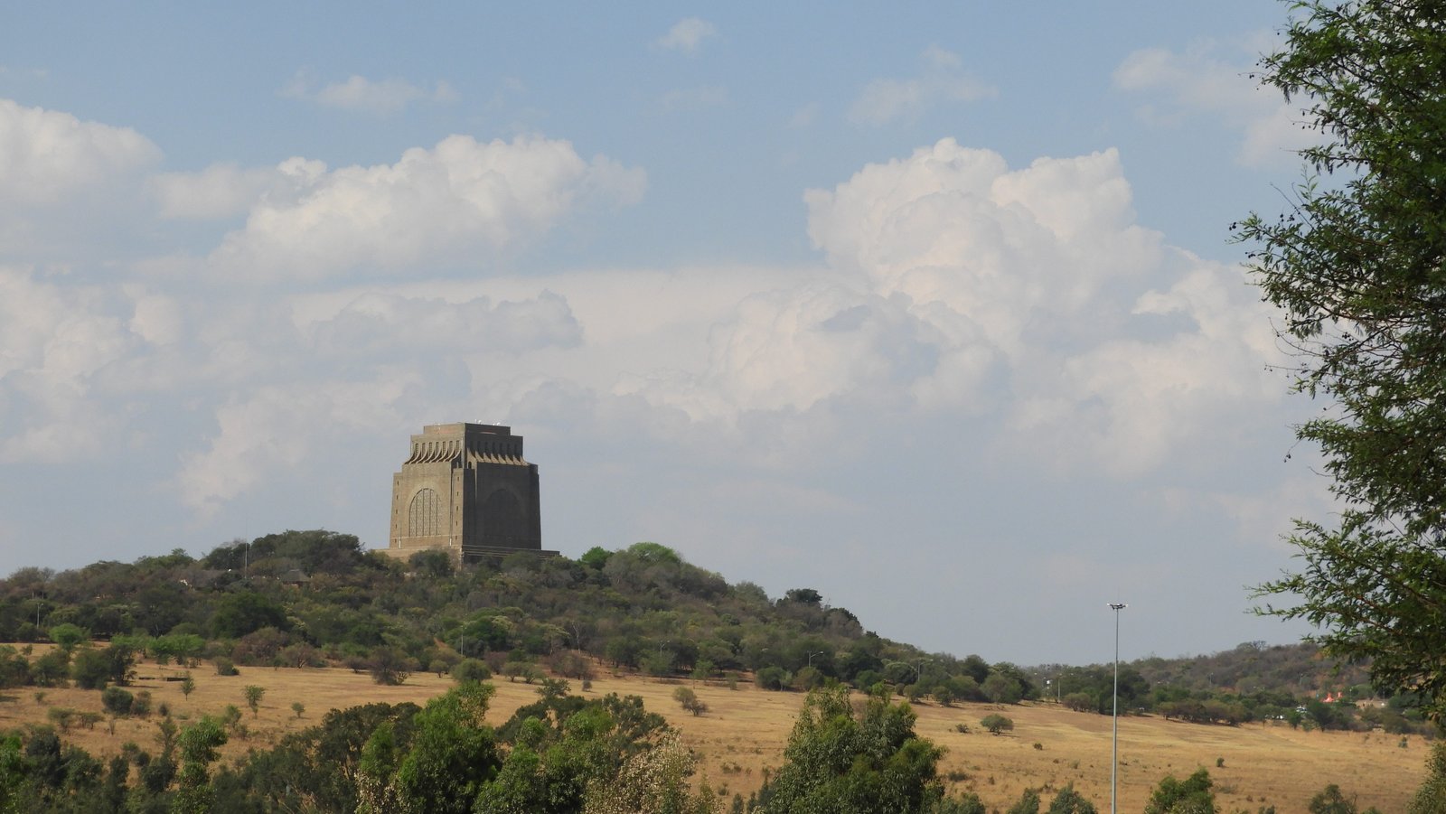 Groen-geel landschap met het Voortrekker-monument opdoemend uit de achtergrond.