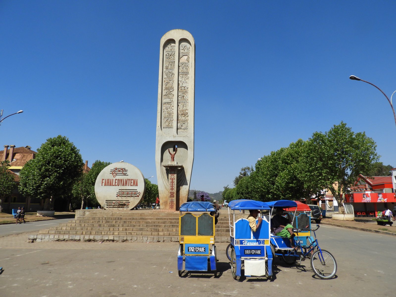 Hoge betonnen paal met afbeeldingen die de 18 etnische groepen van Madagaskar symboliseren.