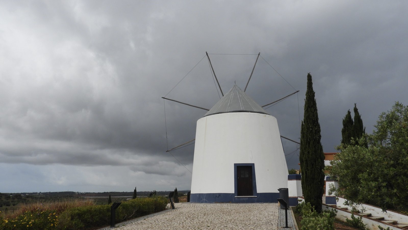 Witte ronde windmolen met bewolkte lucht.