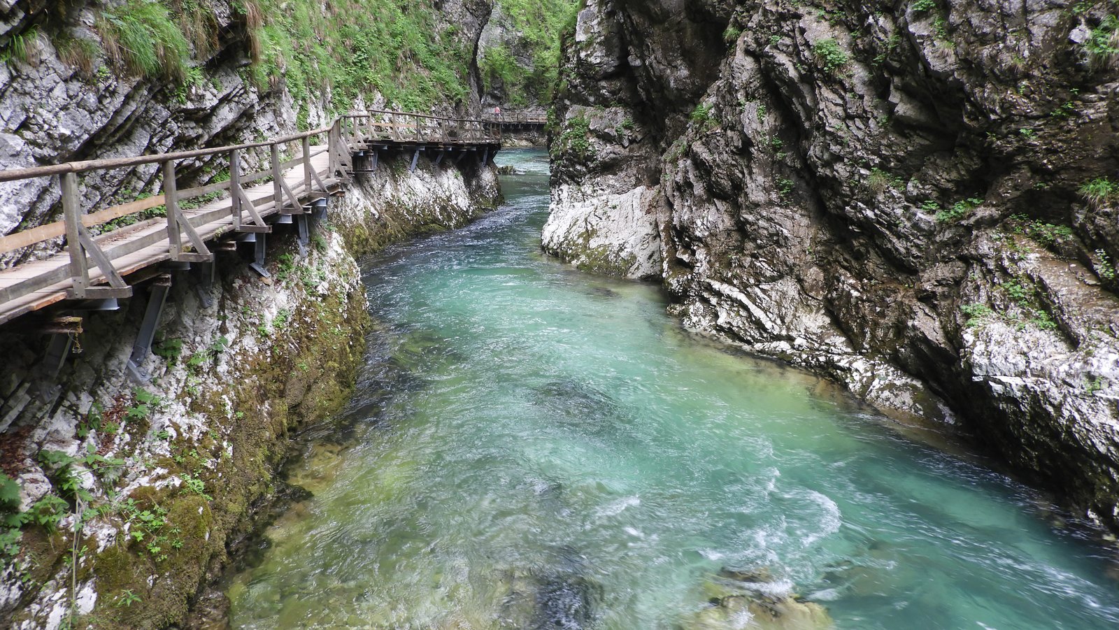 Turquoise rivier in kloof met links houten looppad.