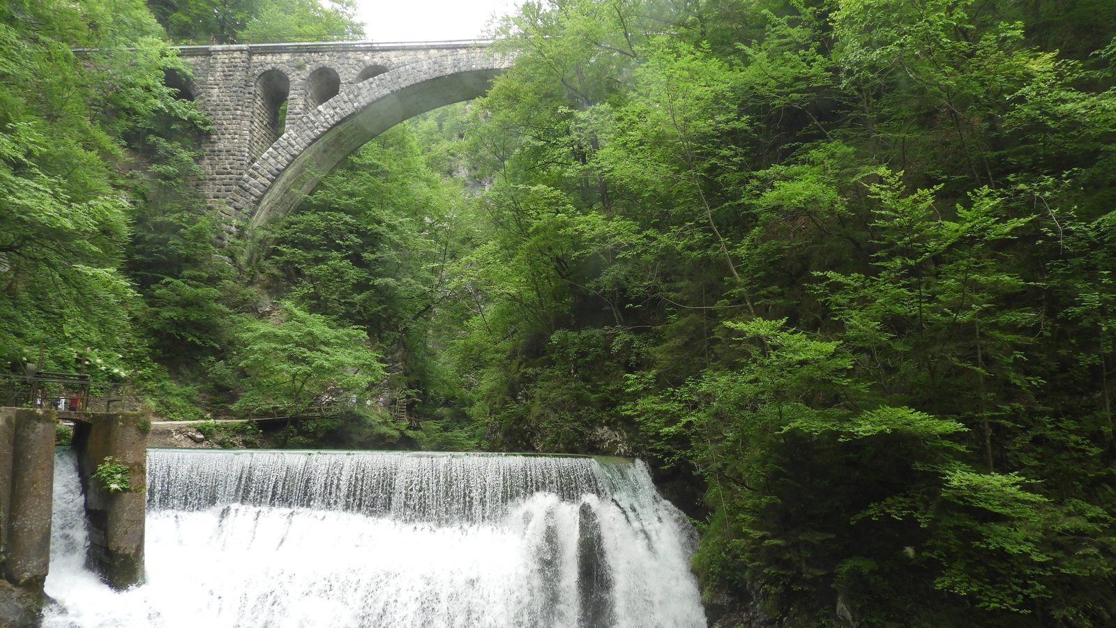 Waterval met hoog daarboven een boogbrug.