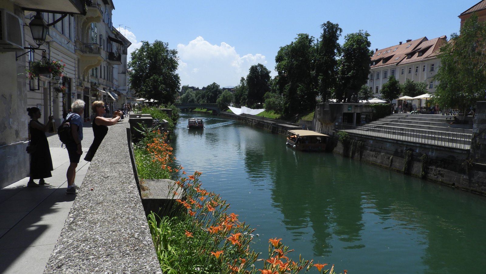 Rivier in de stad met oranje bloemen aan de oever.