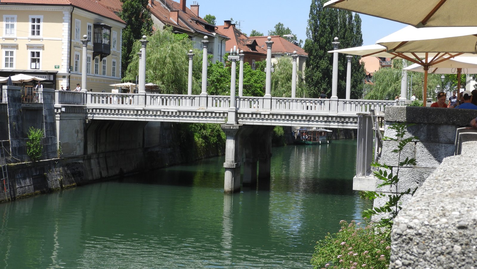 Witte brug met ronde palen er op over rivier.