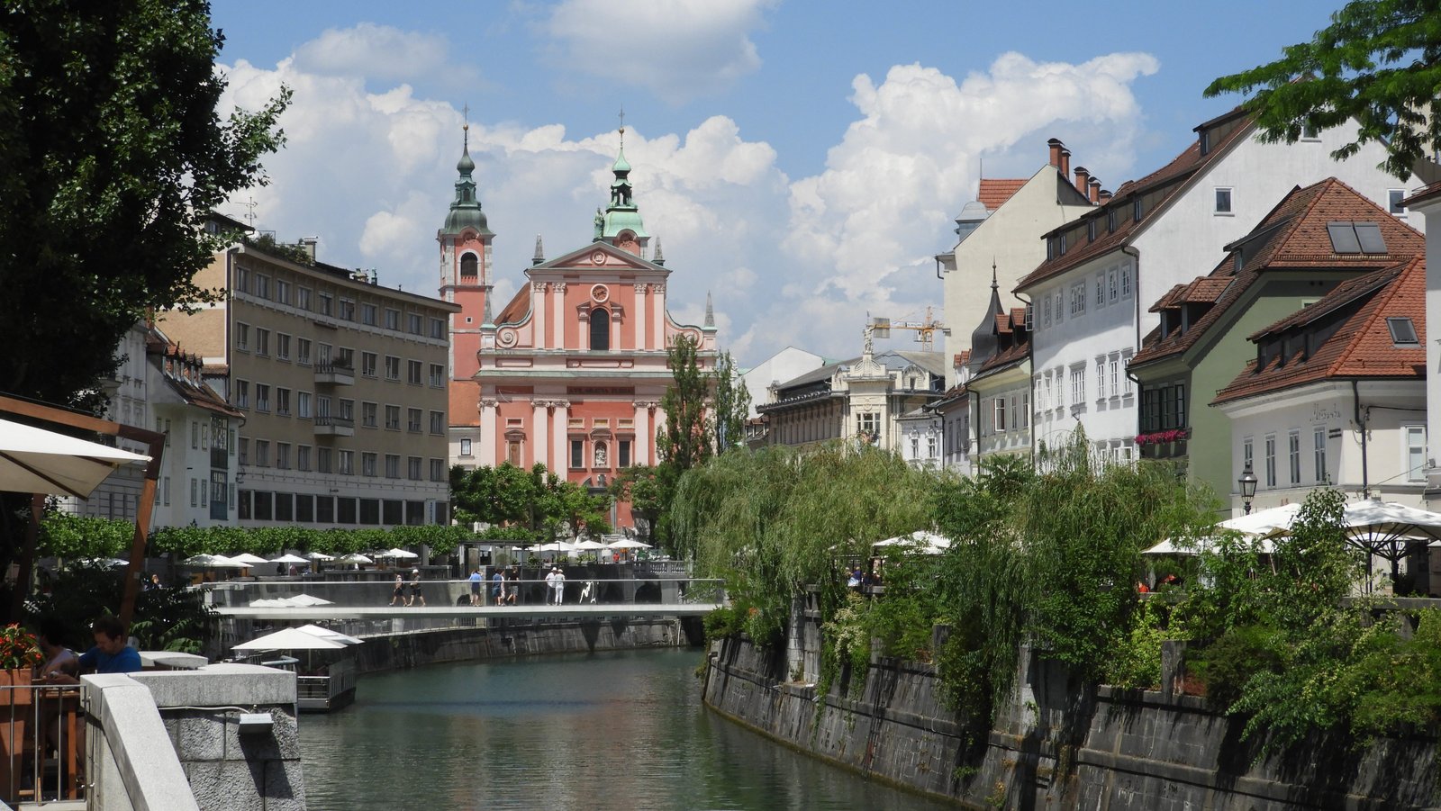 Waterloop en kerk met roze gevel in Ljubljana.