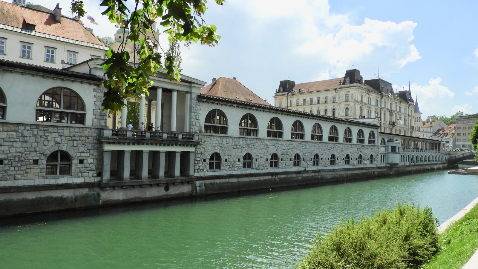 Zicht op statige huizen langs de groene rivier in Ljubljana.