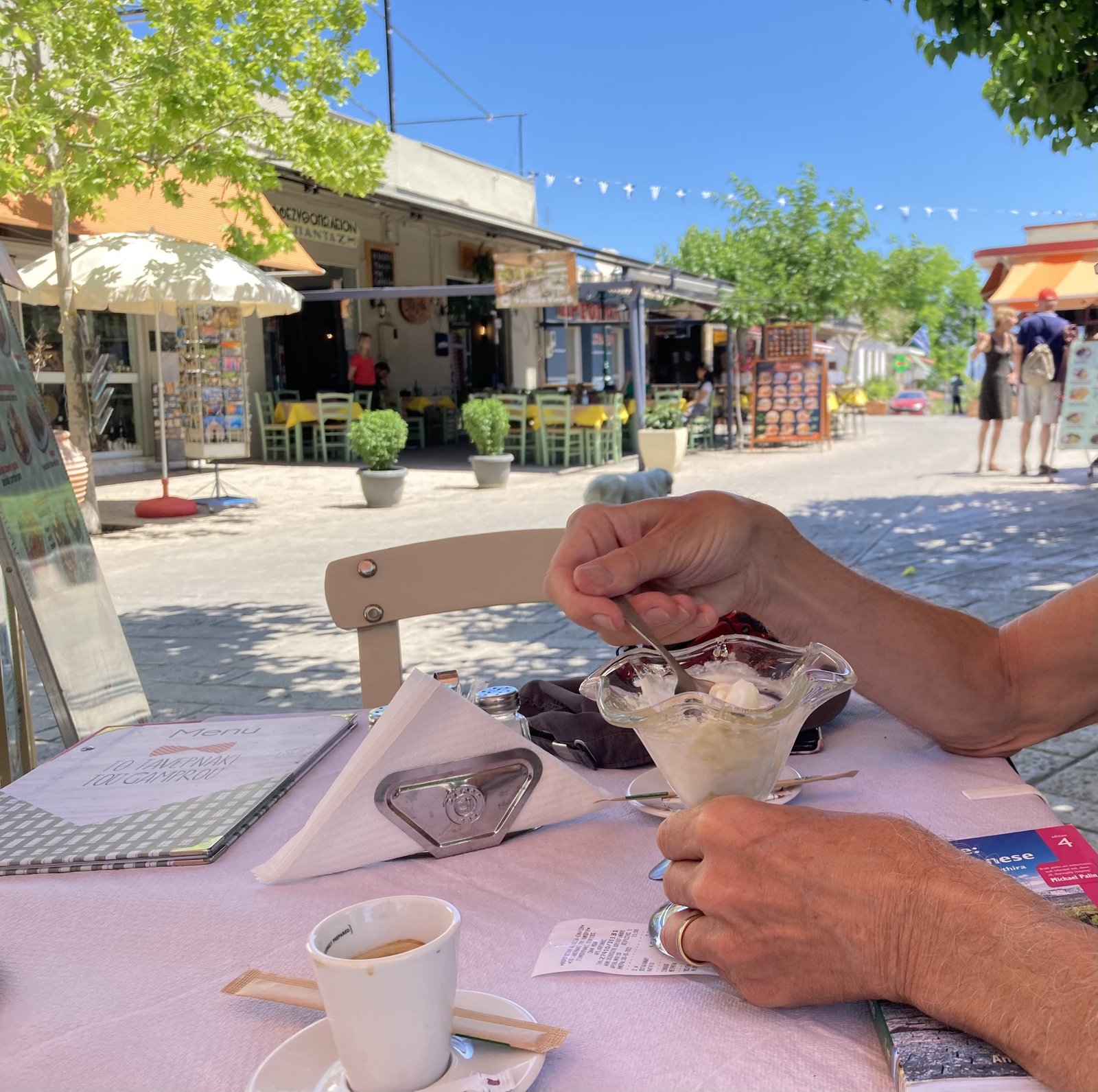 Yoghurt-beker met honing en espresso op terras-tafeltje.