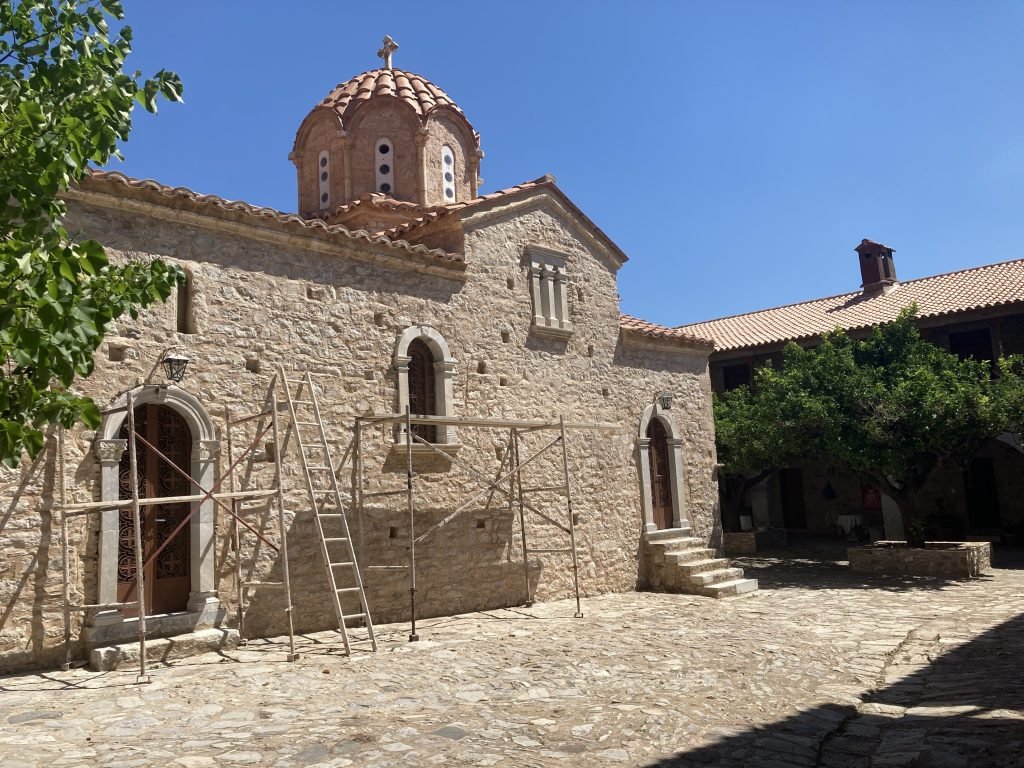 Byzantijns kerkje in grijze natuursteen met stellingen er voor.