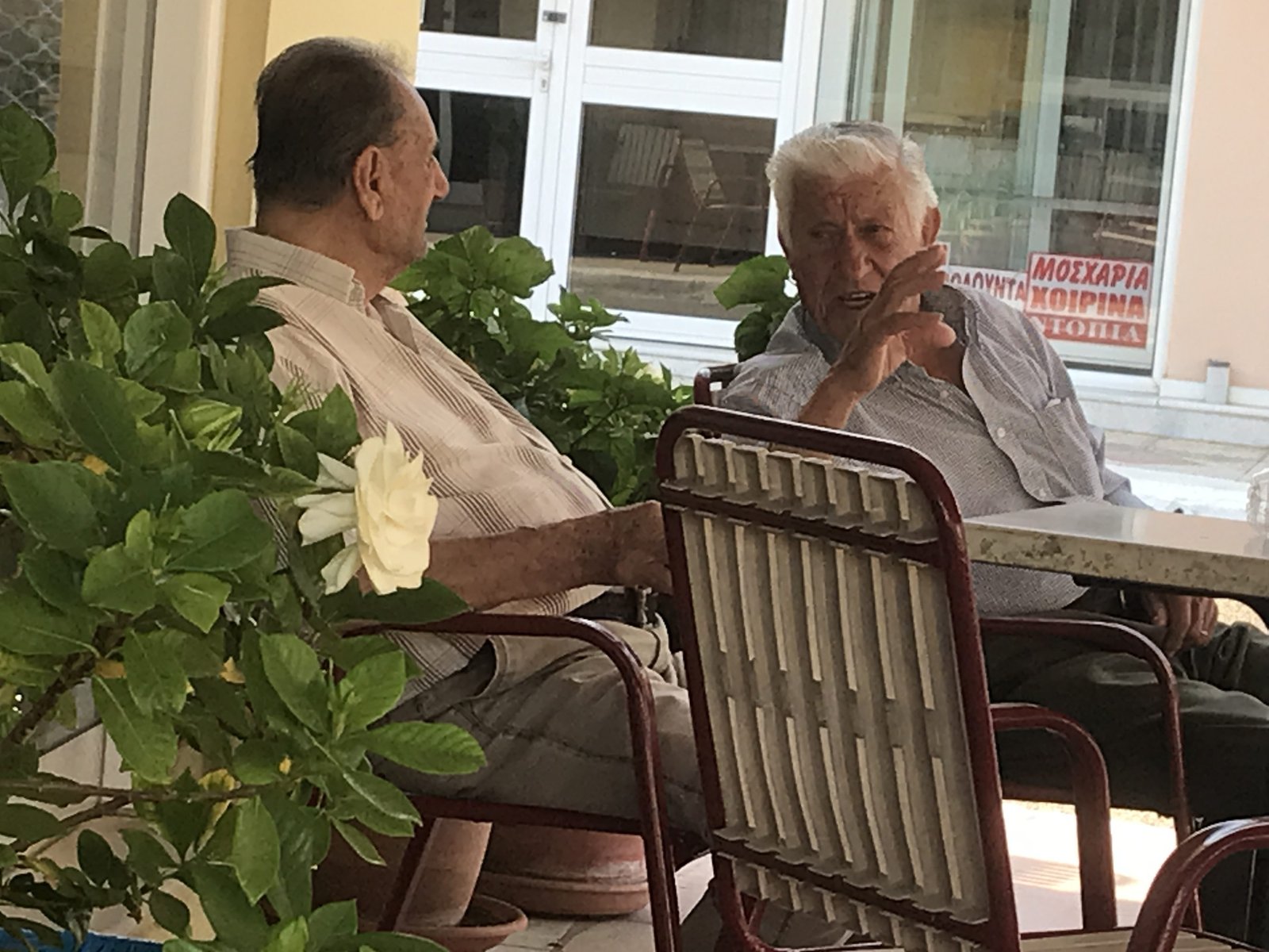 Twee oudere mannen in discussie op café-terras.