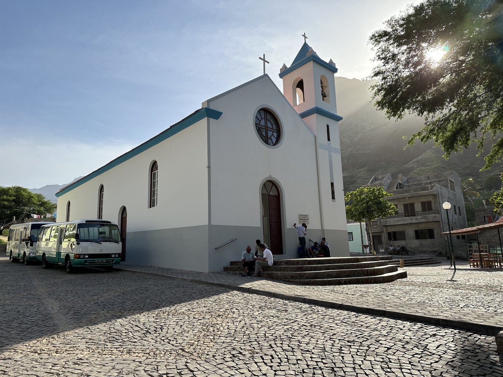 Witte kerk van Chã d'Igreja met twee lokale busjes en een tiental inwoners.