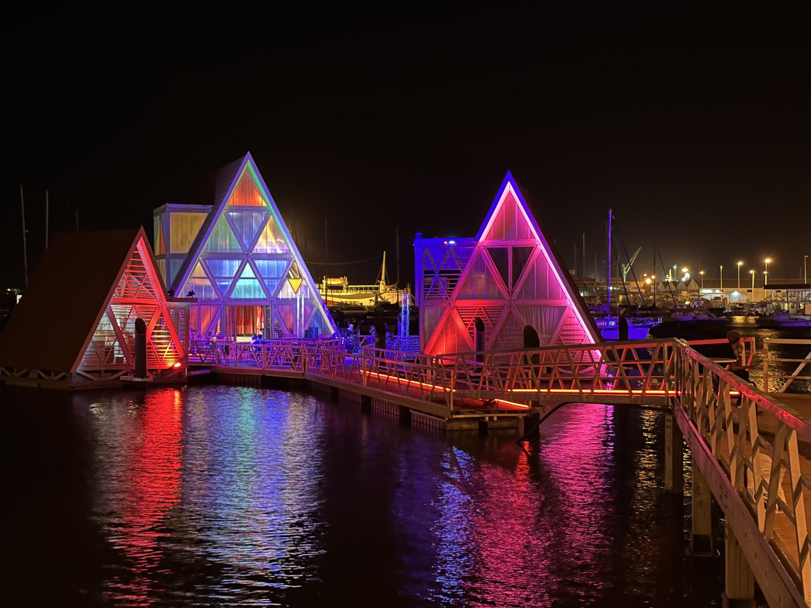 Kleurrijk verlichte driehoekige huisjes bij nacht in de haven van Mindelo.