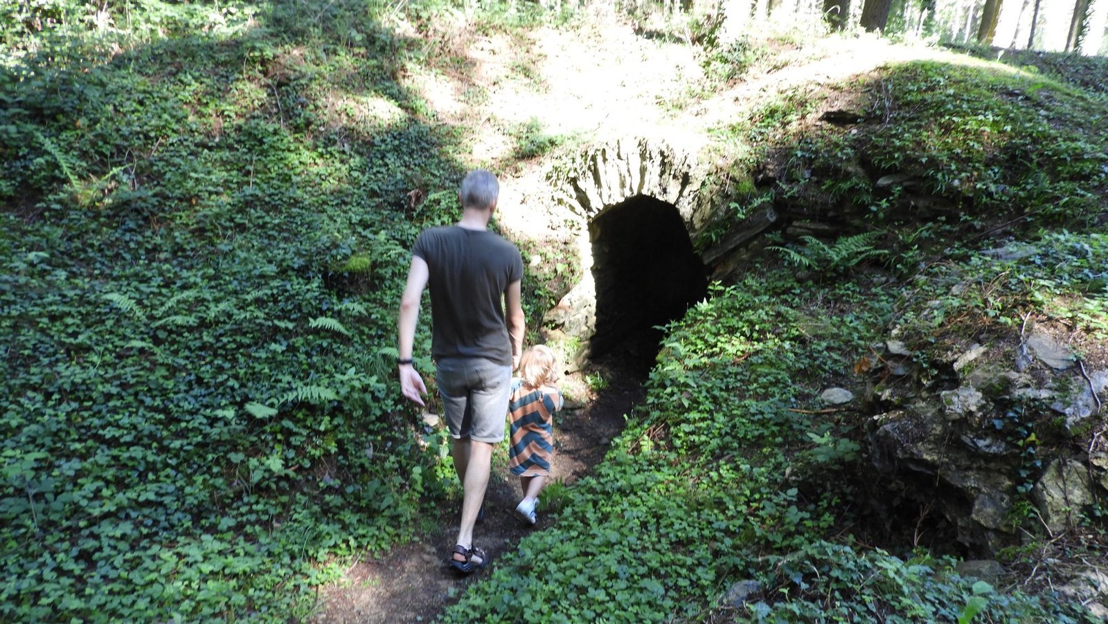Toerist met kindje in holle weg gaat door tunnel stappen.