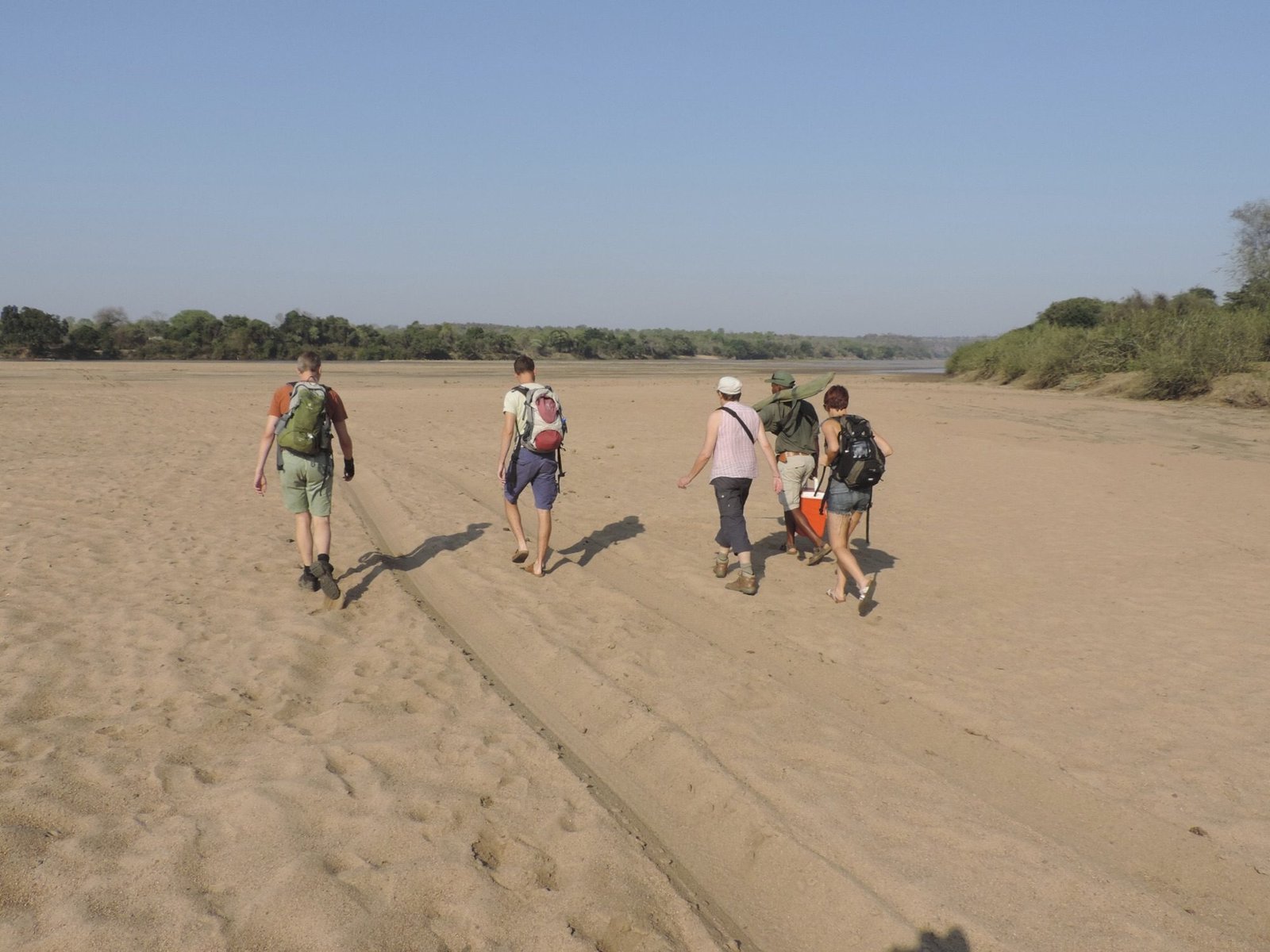 Toeristen op grote zandvlakte van rivier.