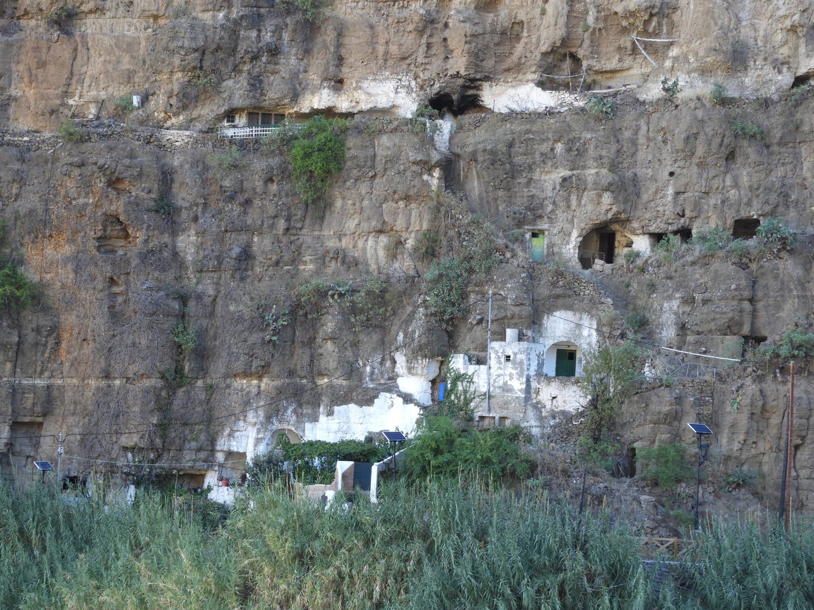 Verticale rotswand met witte huisjes en grotwoningen.