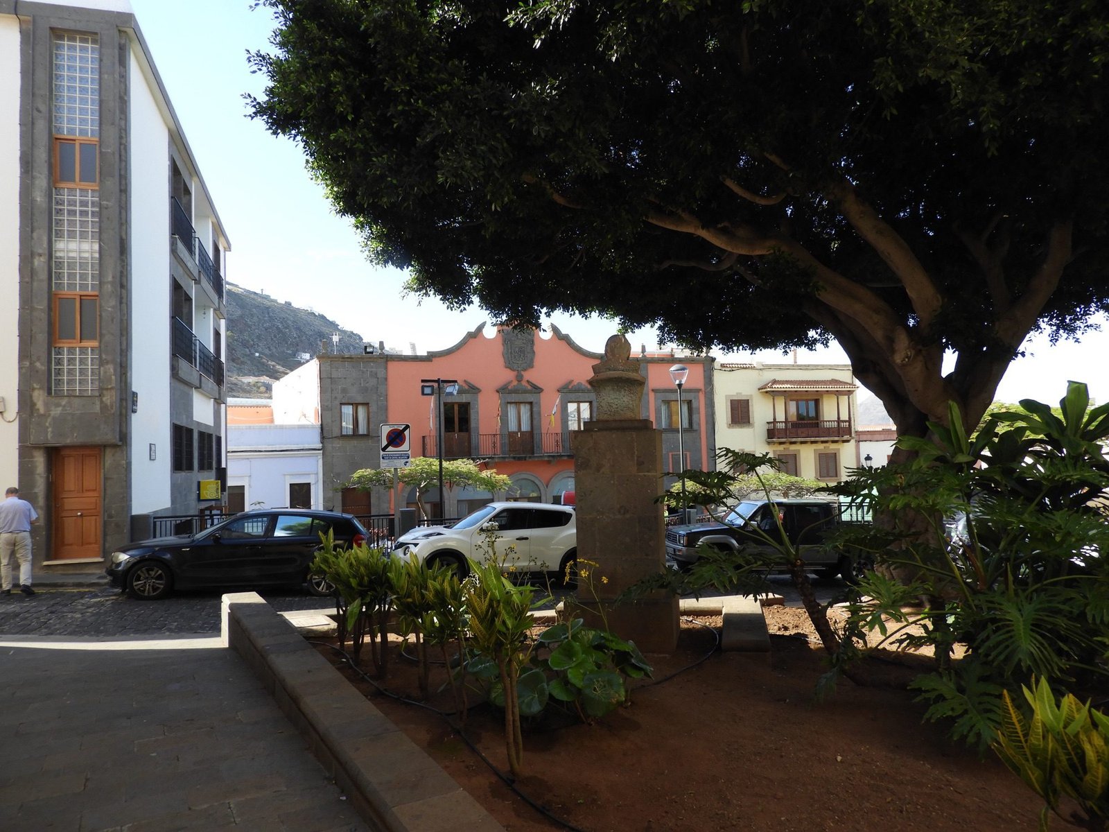 Donker schaduwrijk plein met grote boom in Santa Maria de Guia.