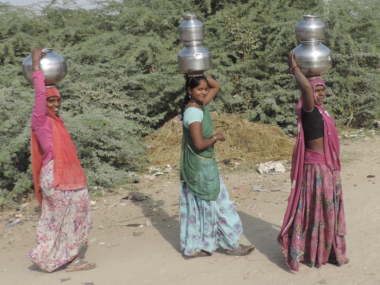 Drie Indiase vrouwen met kruiken op het hoofd.