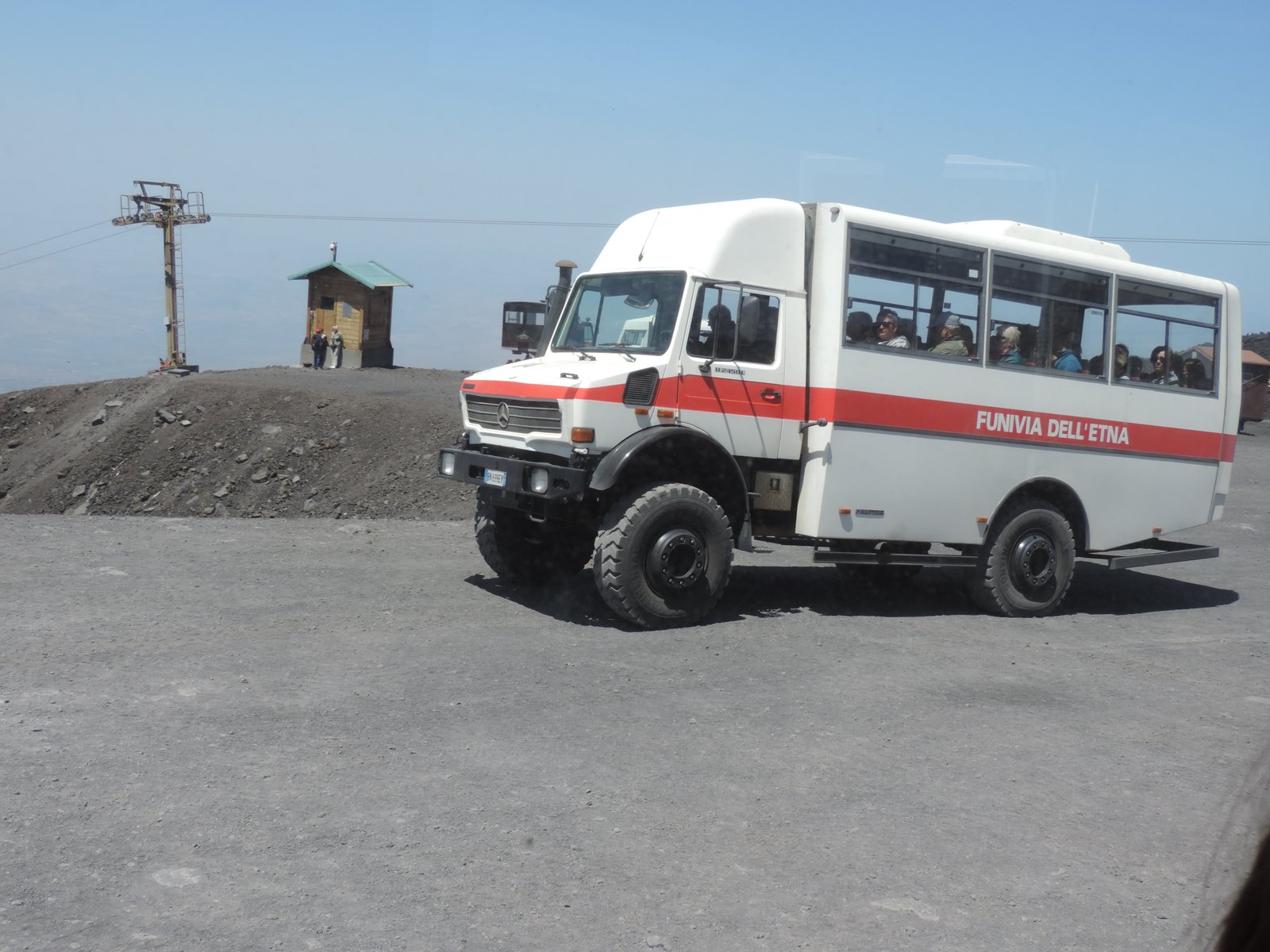 Witte jeep-bus in lava-grijze omgeving.