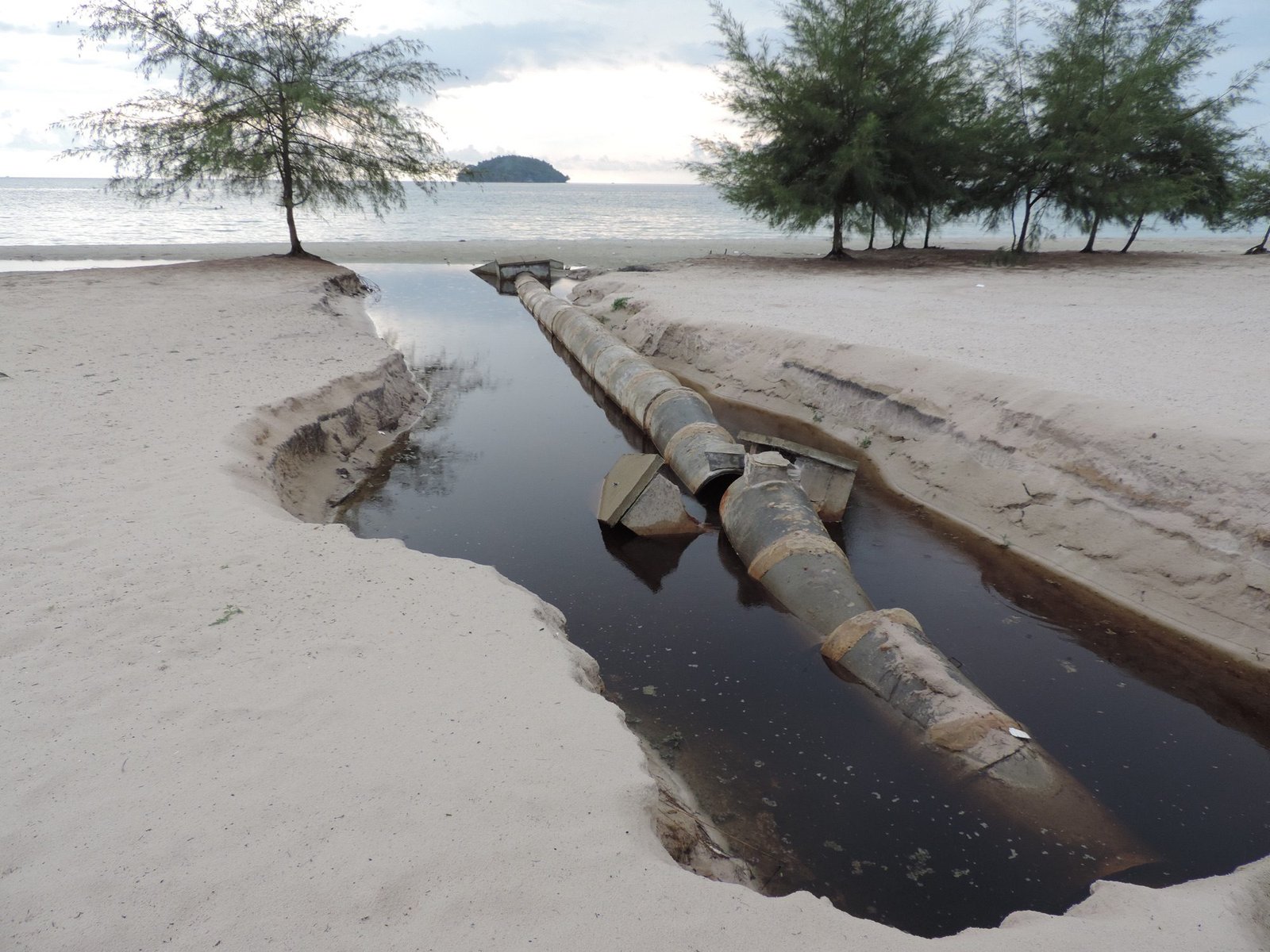 Gebroken rioolbuis op strand.