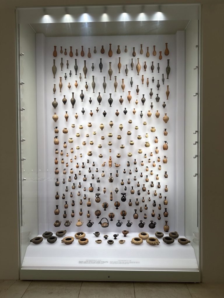 Polycentric museum Aigai: honderden kleine vaasjes op een verticale verlichte wand