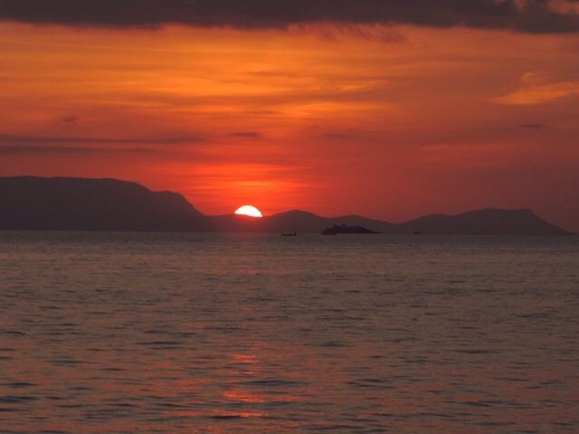 Donkerrode zonsondergang boven zee.