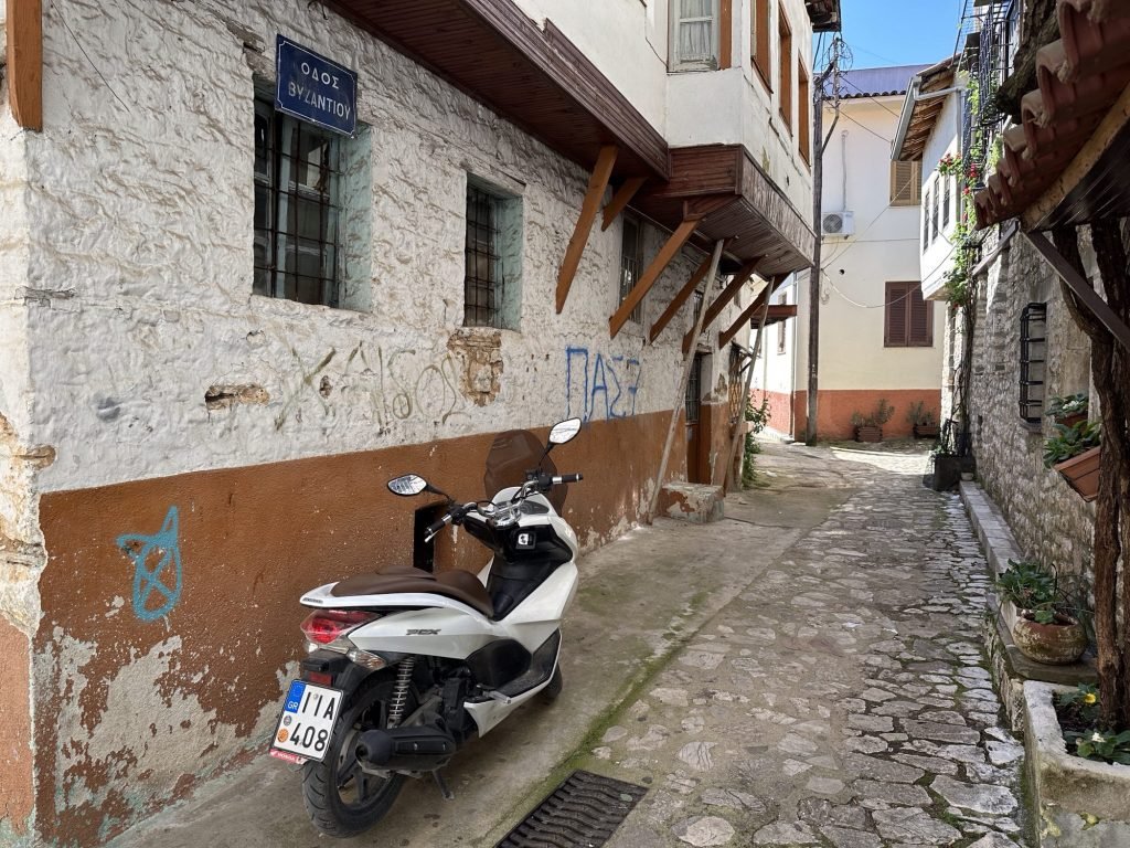 Kasseistraatje met heel oude huizen en vespa in Ioannina, Centraal Griekenland