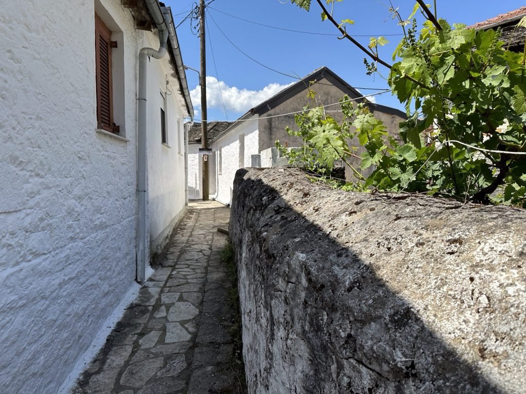 Smal straatje met brede muur in Nissaki, Ioannina, Centraal Griekenland