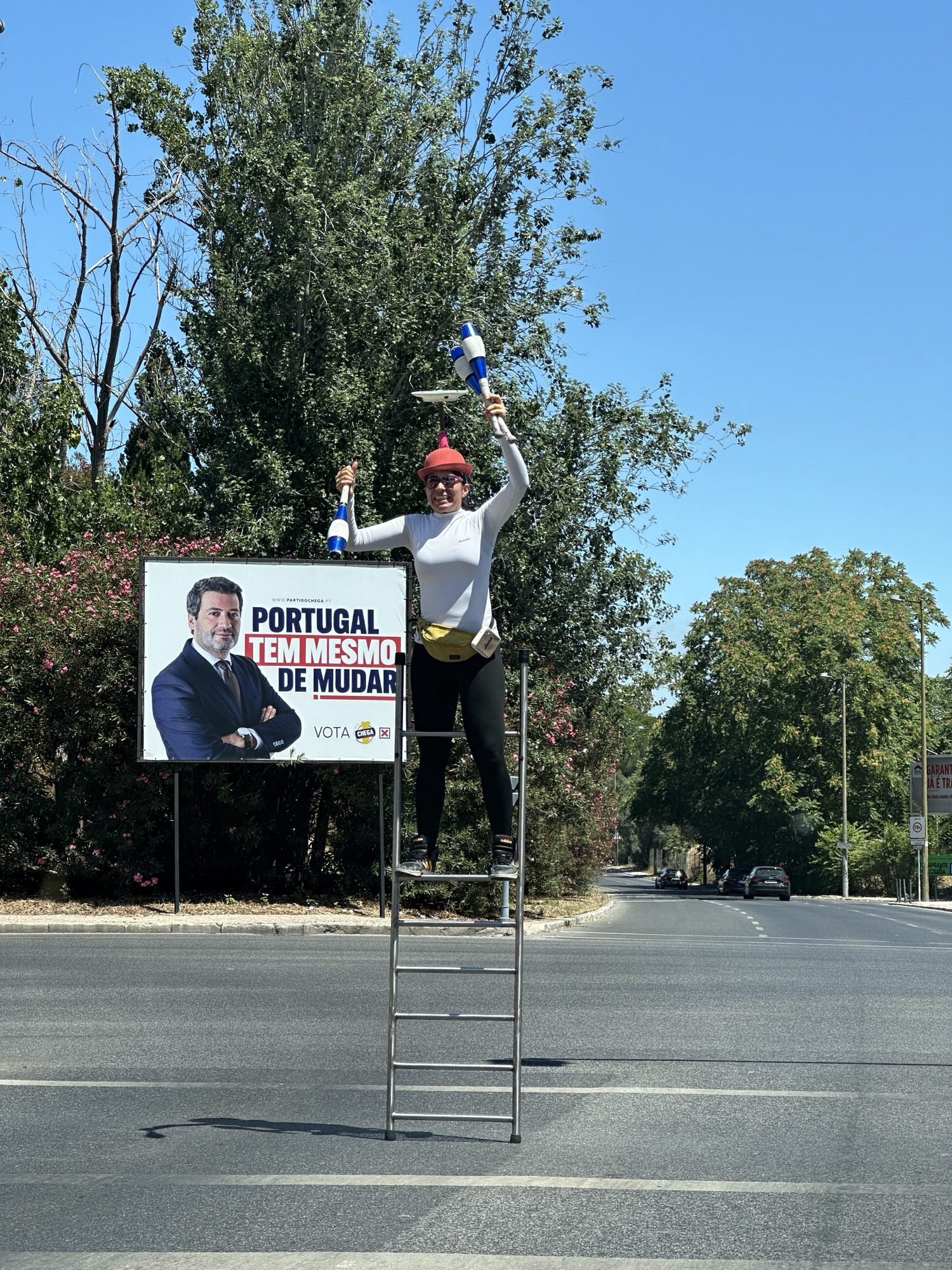 Jongleur op ladder naast politiek campagne-bord.