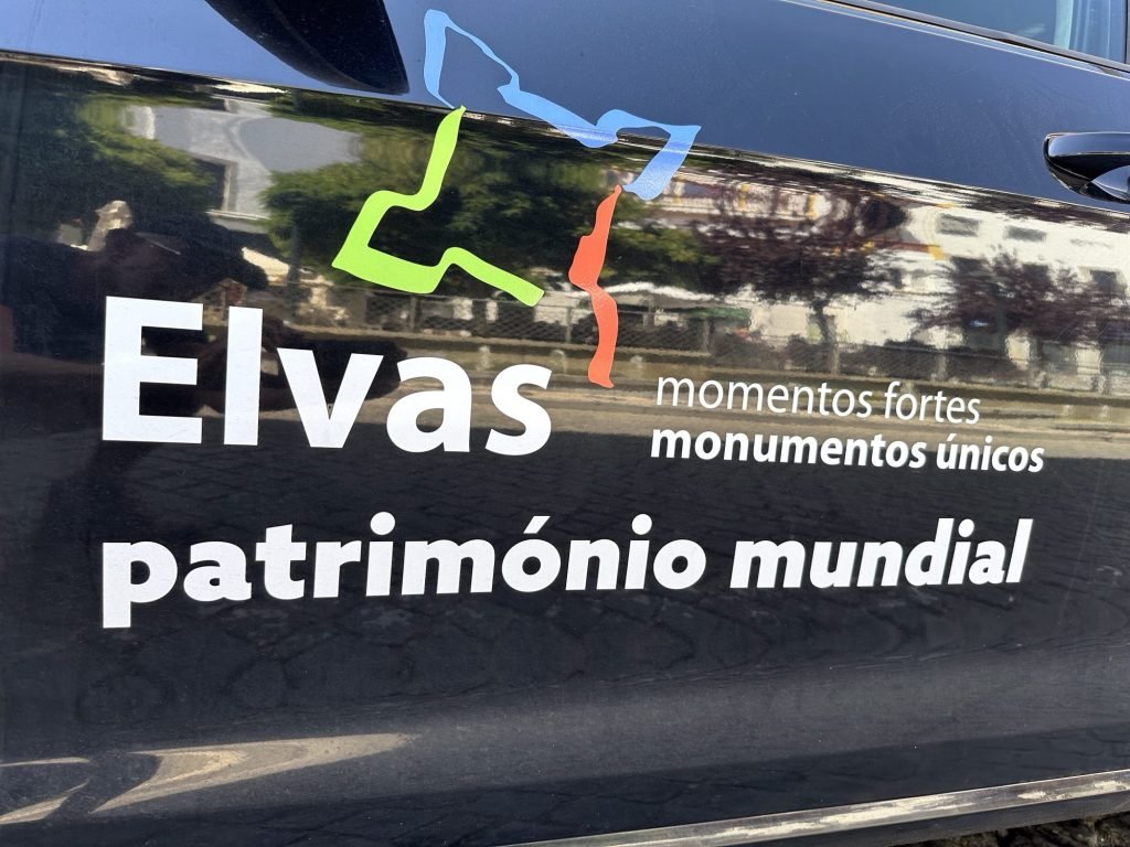 Reclame voor Elvas op portier van auto met weerspiegeling van historische straat 