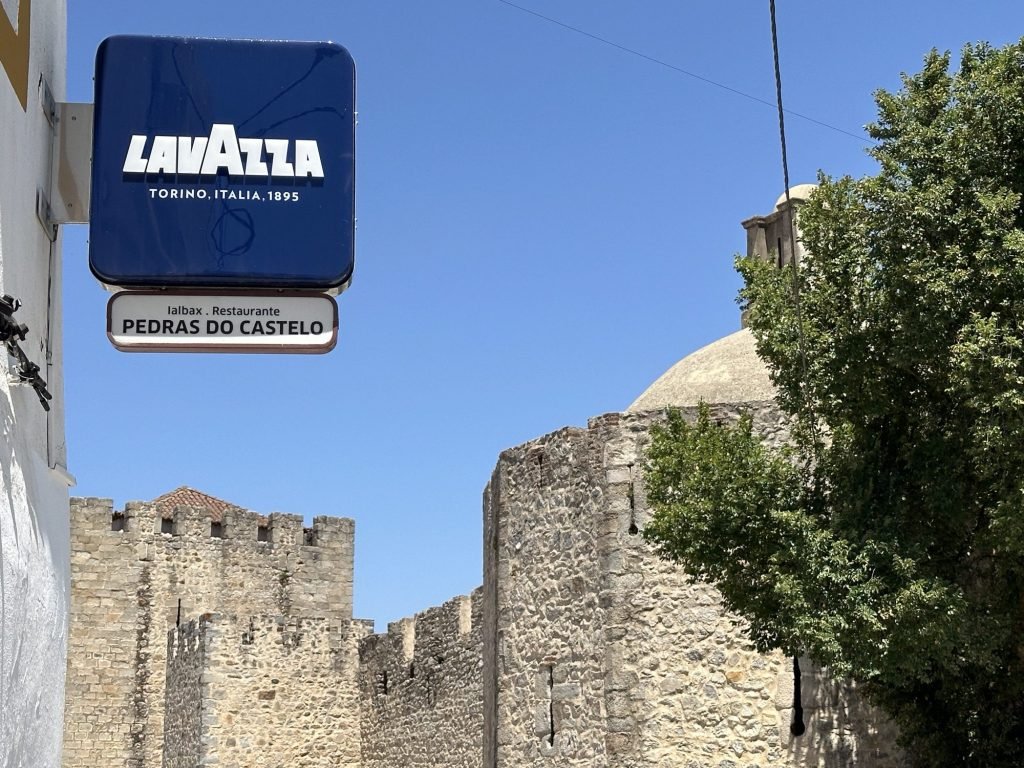 Zicht op de muren van het Castelo in Elvas met Lavazza uithangbord en naam: Pedras do Castelo