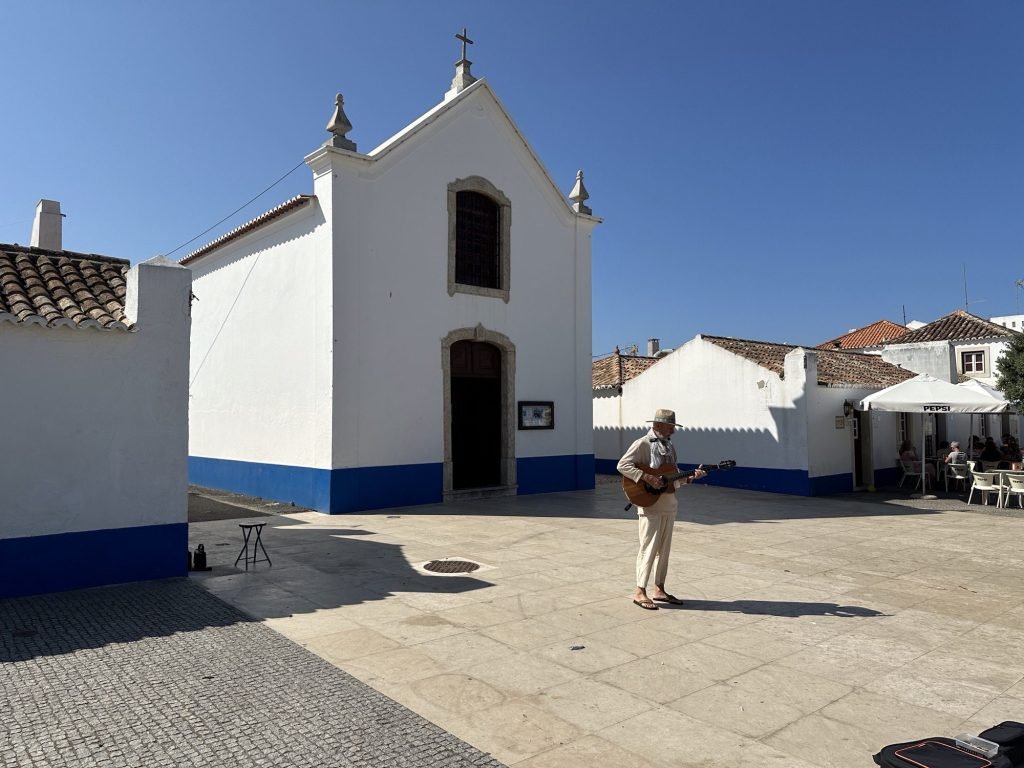 Wit kerkje met straatzanger in Porto Covo